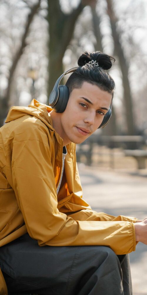 Teenage boy sitting in park with headphones.